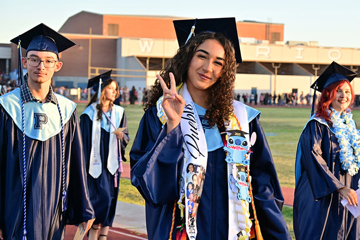 Graduates smile as they walk into the stadium