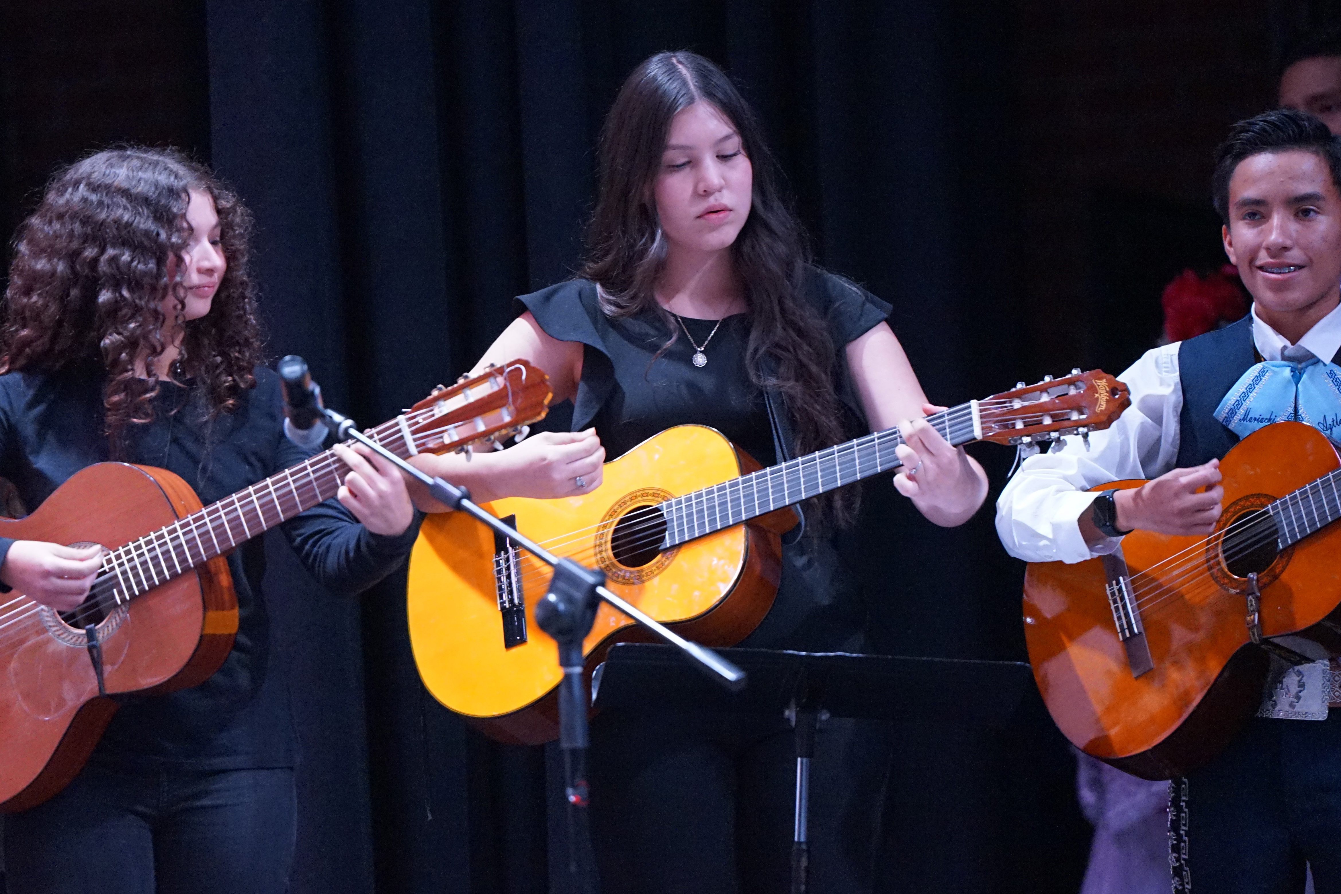 Two girls and a boy play their guitars