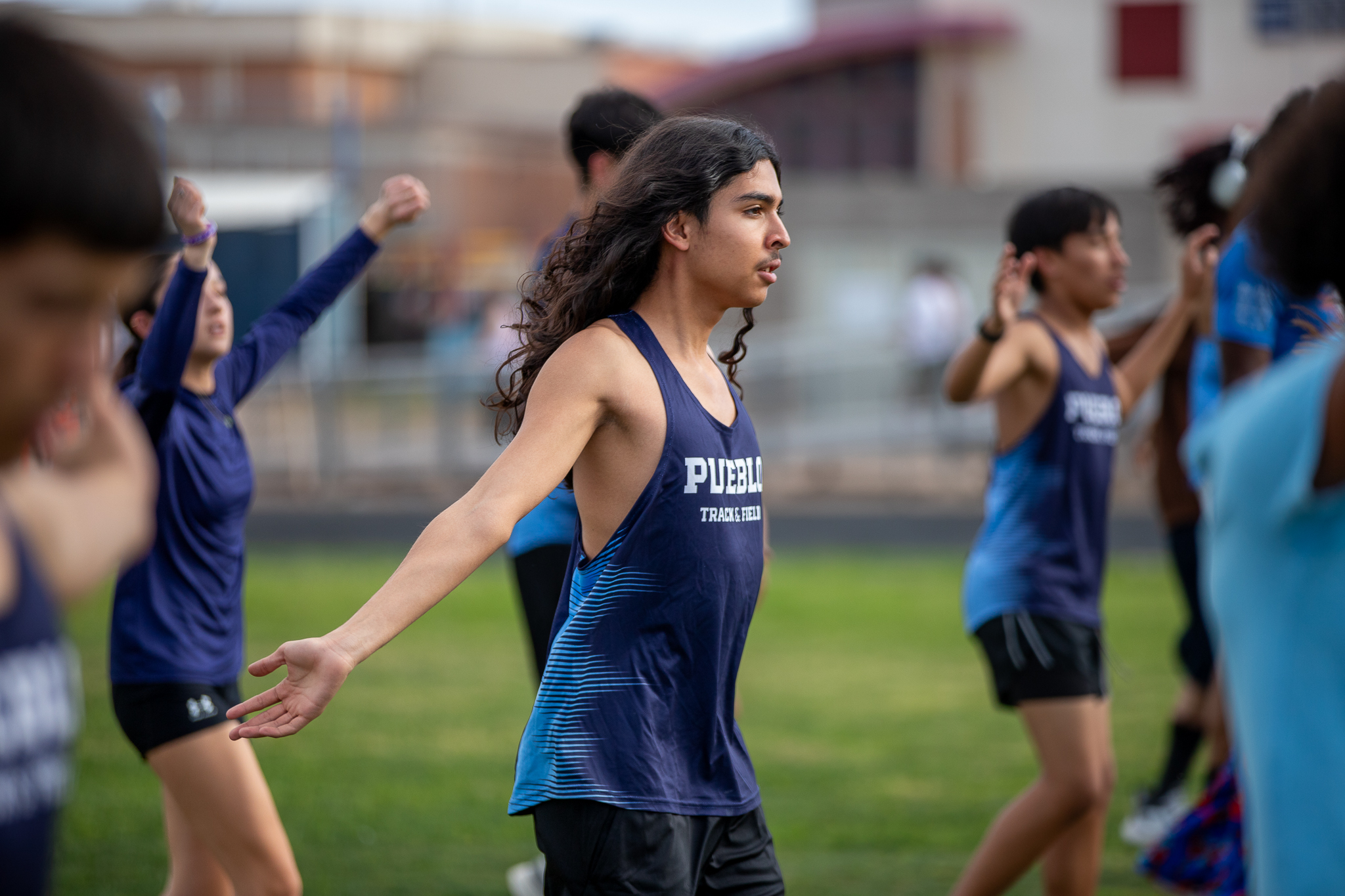 The Pueblo track team stretches on the field