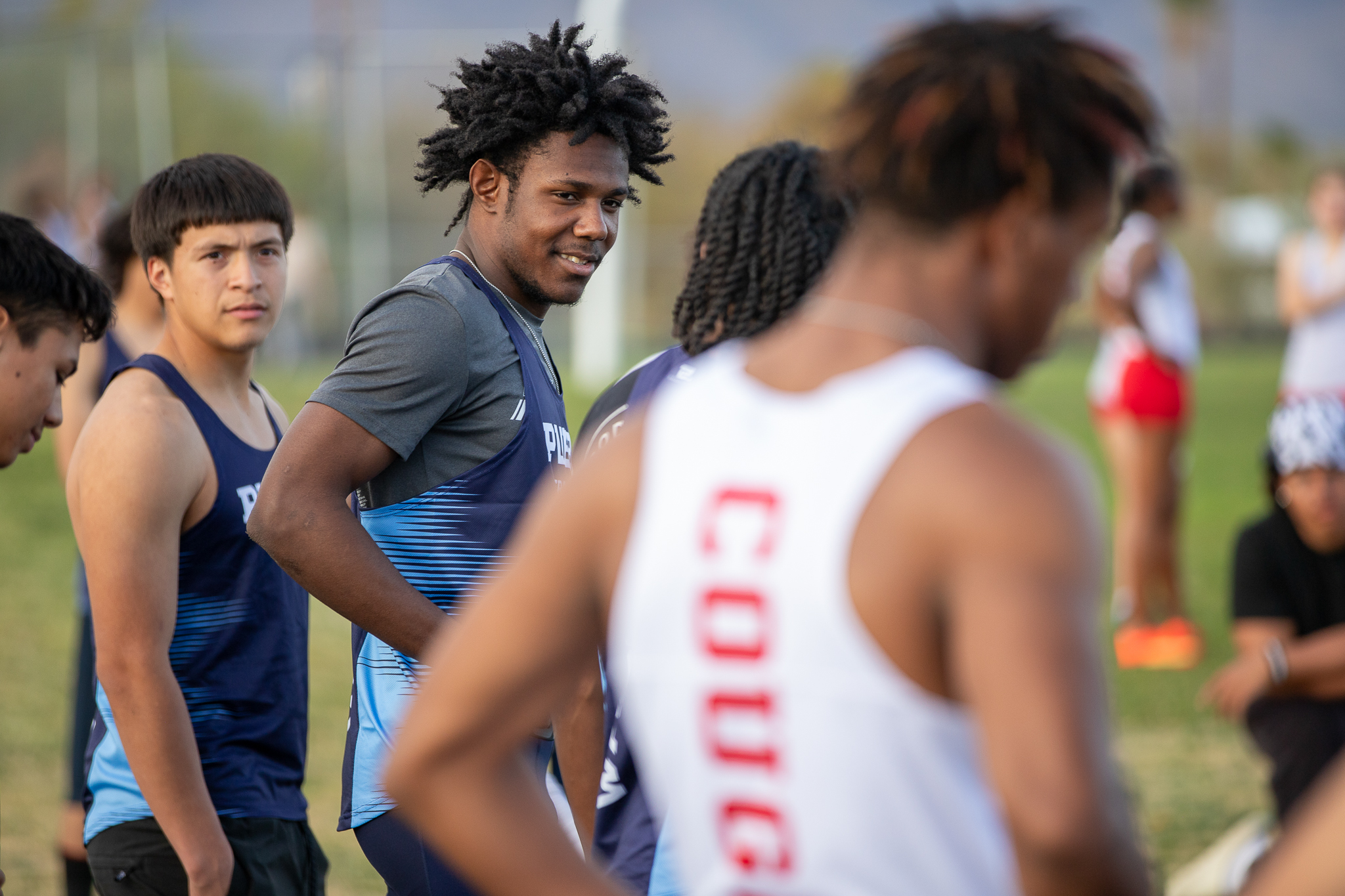 Three boys from the Pueblo track team talk on the field together