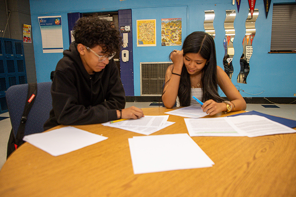 A teen boy and teen girl work together on an assignment