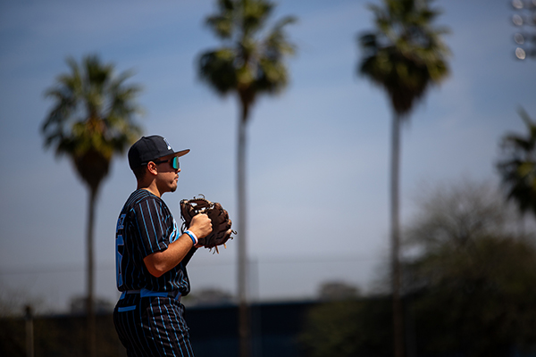 A teen boy stands in the outfield, ready to catch a ball