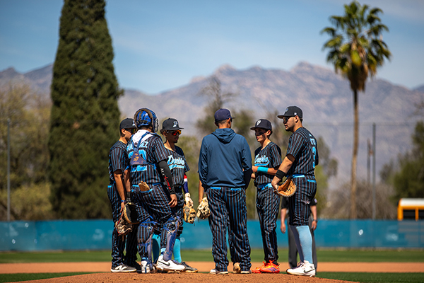 The baseball team huddles at the pitcher's mound