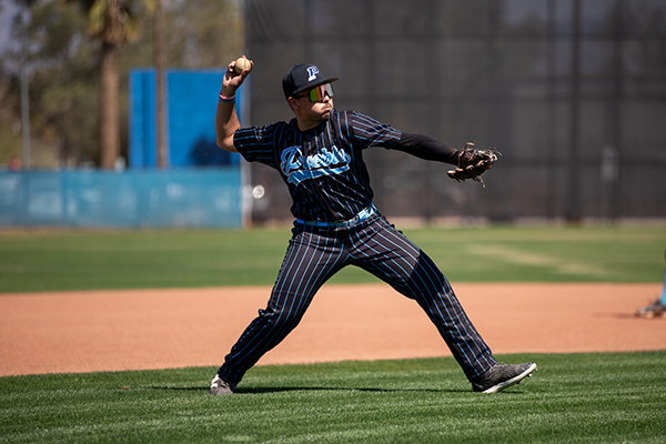 A teen boy throws the baseball from the outfield