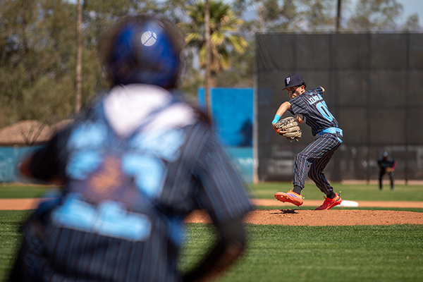The pitcher, back, gets ready to throw the ball, while the catcher, front, waits