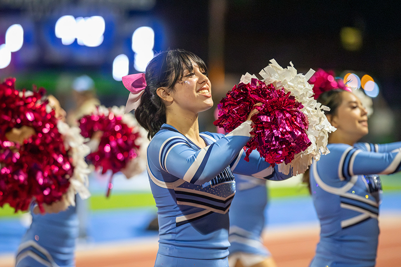 Teen girls perform a cheer with red and white pom poms
