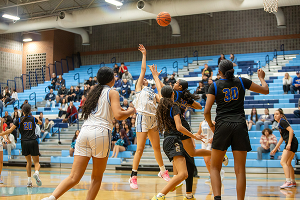 A Pueblo girl tosses the basketball high into the air