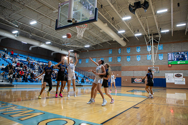 A Pueblo girl shoots the ball into the basket as her opponents jump up to try to block the shot