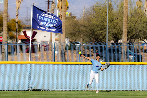 A teen girl throws the softball from the outfield