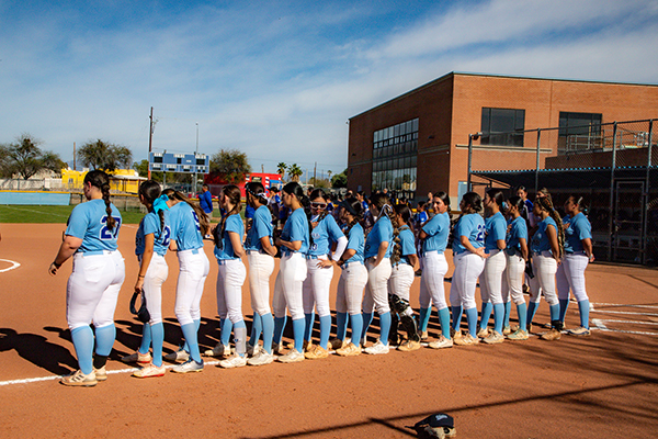 The girls softball team stands on the sidelines