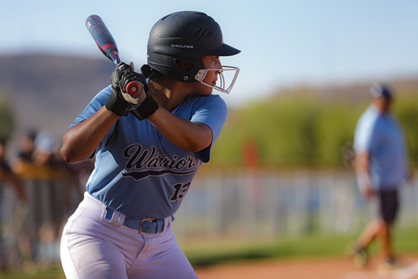 A teen girl holds the bat, ready to swing at the softball