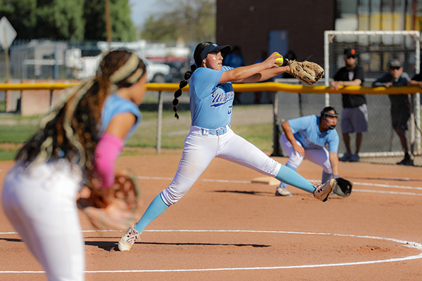 A teen girl winds up to pitch the softball