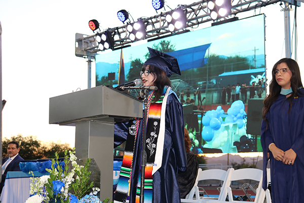 A graduate addresses her class on stage during the ceremony