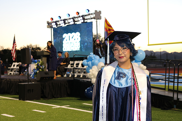 A graduate smiles as she stands in front of the stage during the ceremony