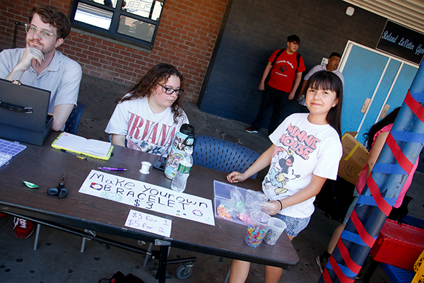 A girl smiles at a table where you can make your own bracelets