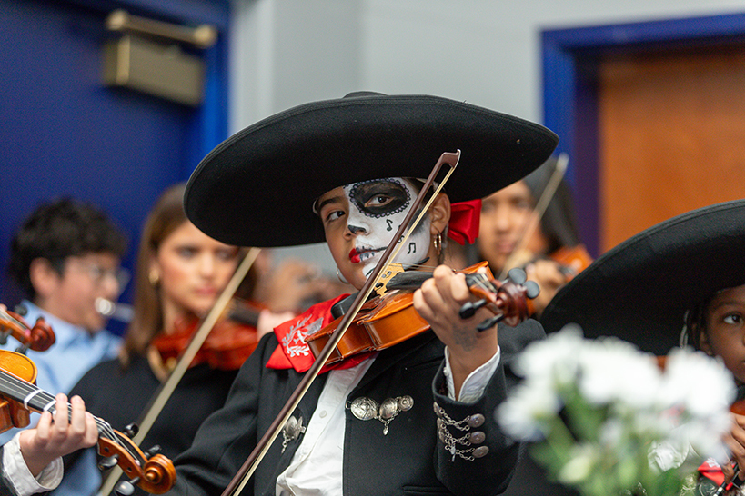 A student in Dia de los Muertos makeup plays violin