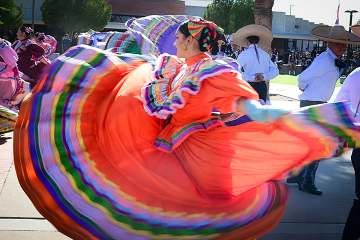 A teen girl twirls her red folklorico dress as she dances