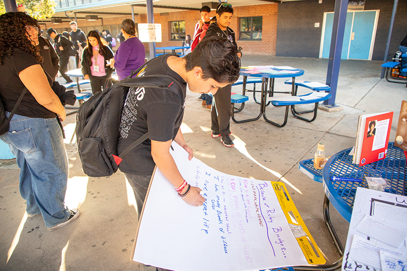 A student writes on a sheet of paper about what he can do because of Ruby Bridges