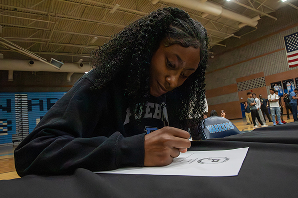 A teen girl signs her college letter of intent