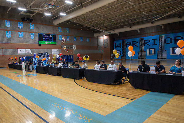 Students sit at tables waiting to sign their letters of intent