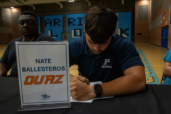 A teen boy signs his college letter of intent