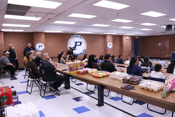 People sit in a cafeteria watching a presentation